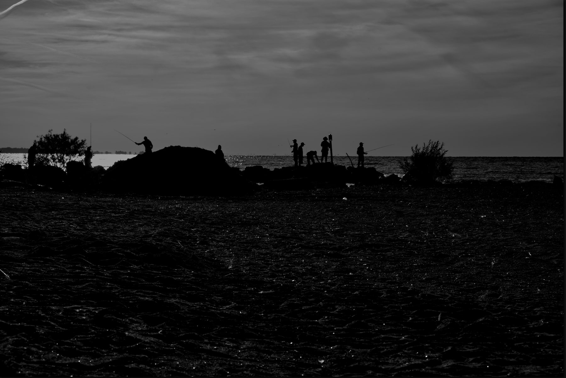 a silhouette of a gaggle of fisherman on a beach