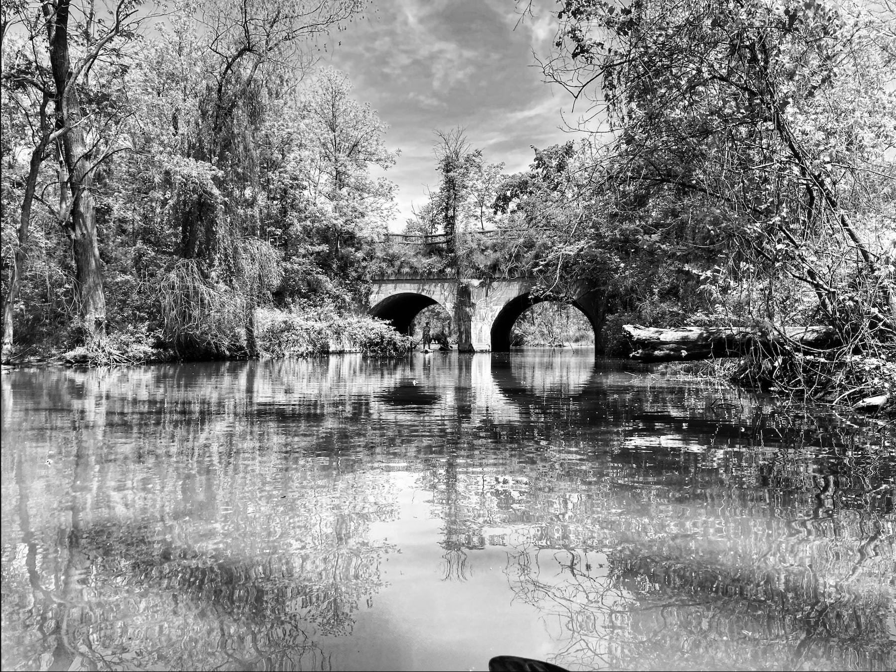 a paddle boarder appears under the arch of an old railway bridge