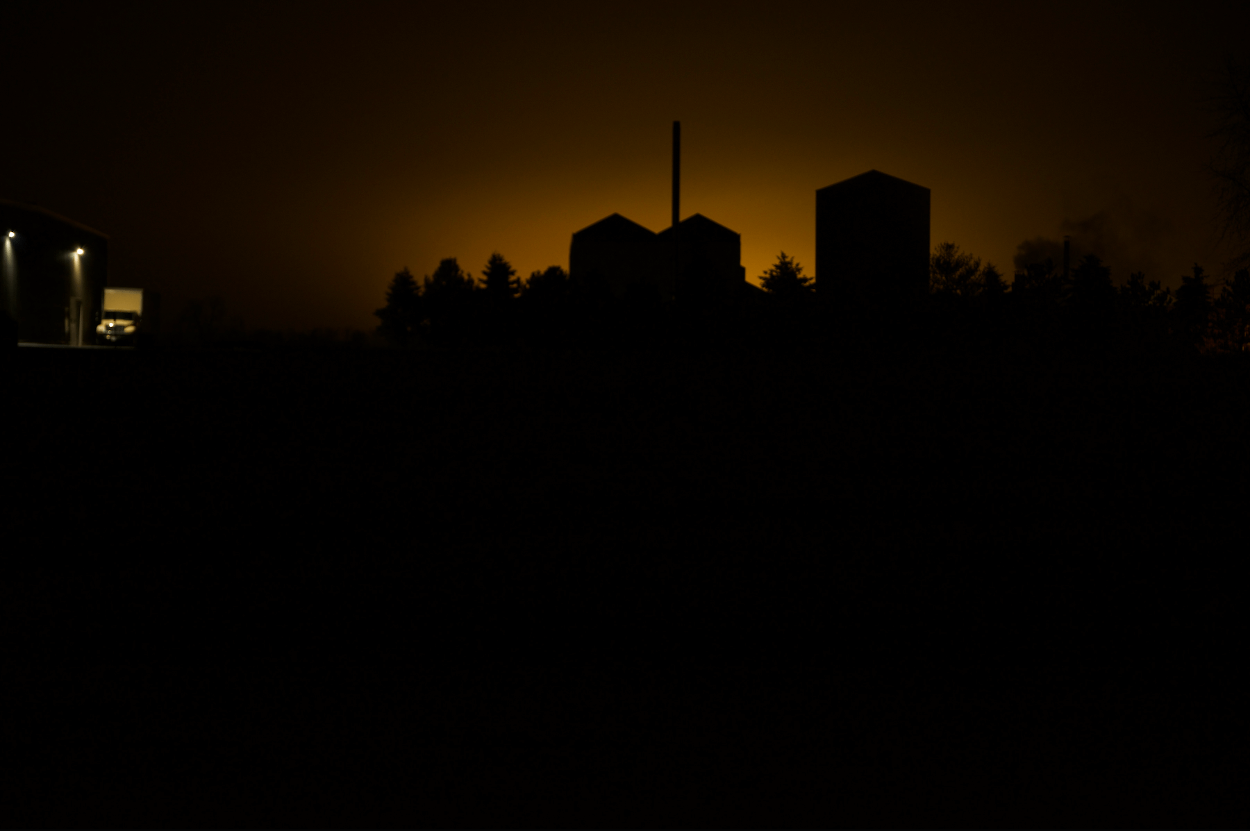 a silhouette of some weird building with a truck illuminated by the rising sun