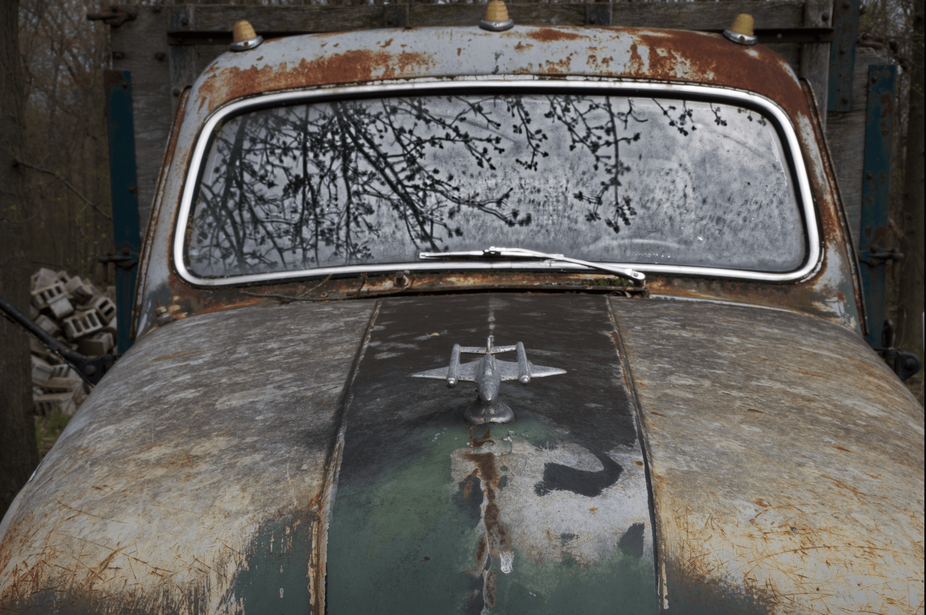 a close up of an abandoned 1 ton truck with crazy reflection on the windshield.