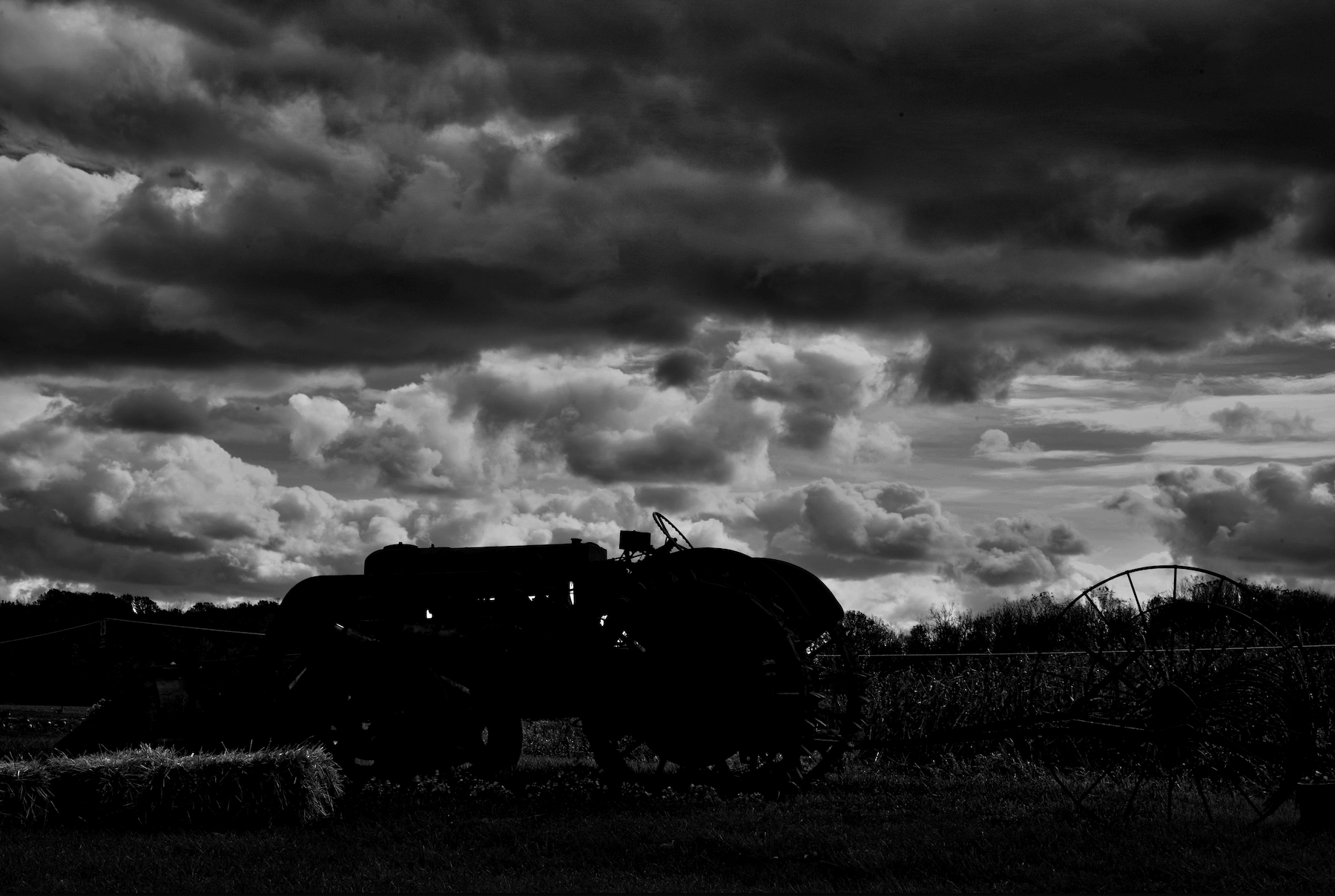 a silhouette of an old tractor and attached rake