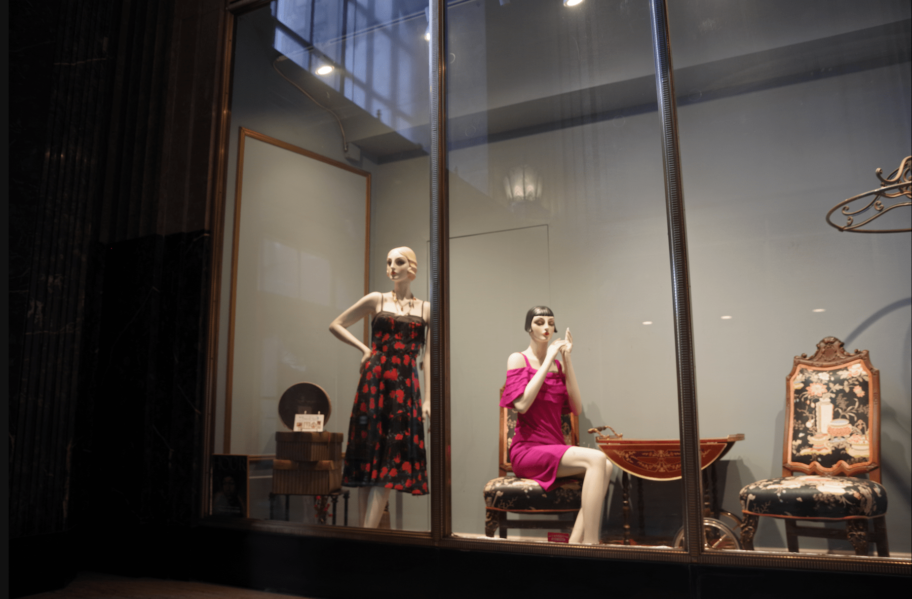 a color photograph of Two female mannequins in a store front window dressed in early 1920's period clothing