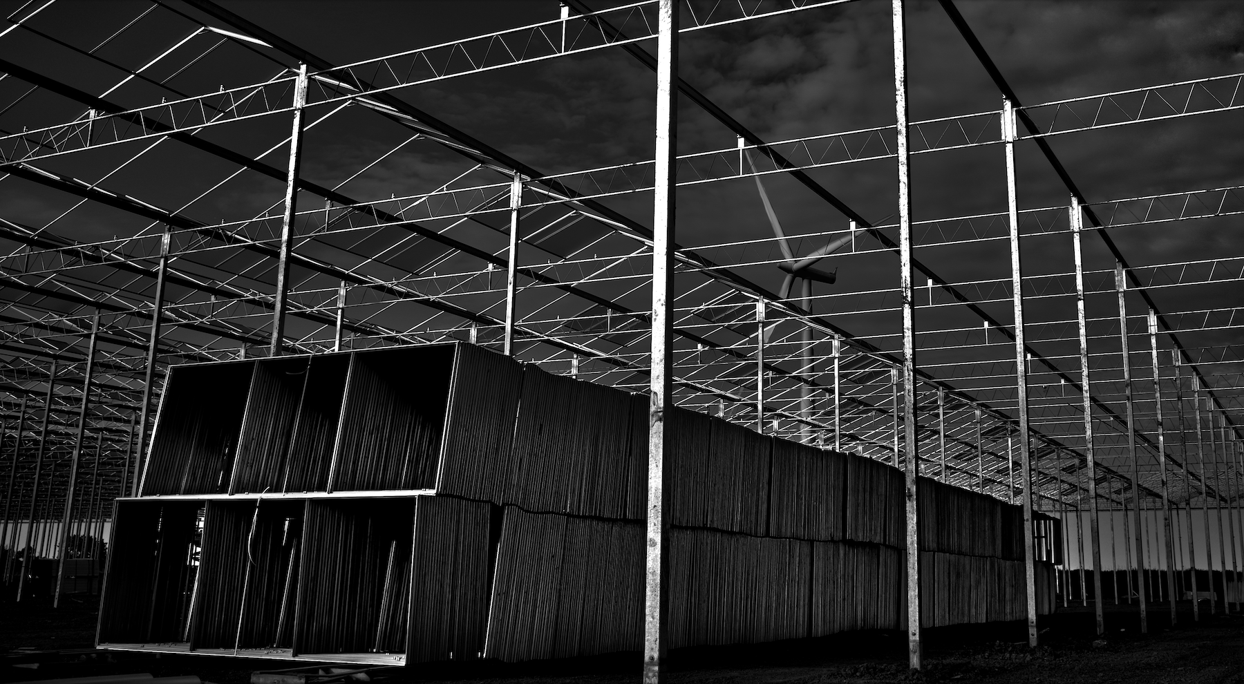 a black and white photography showing the metal framework of a greenhouse under construction