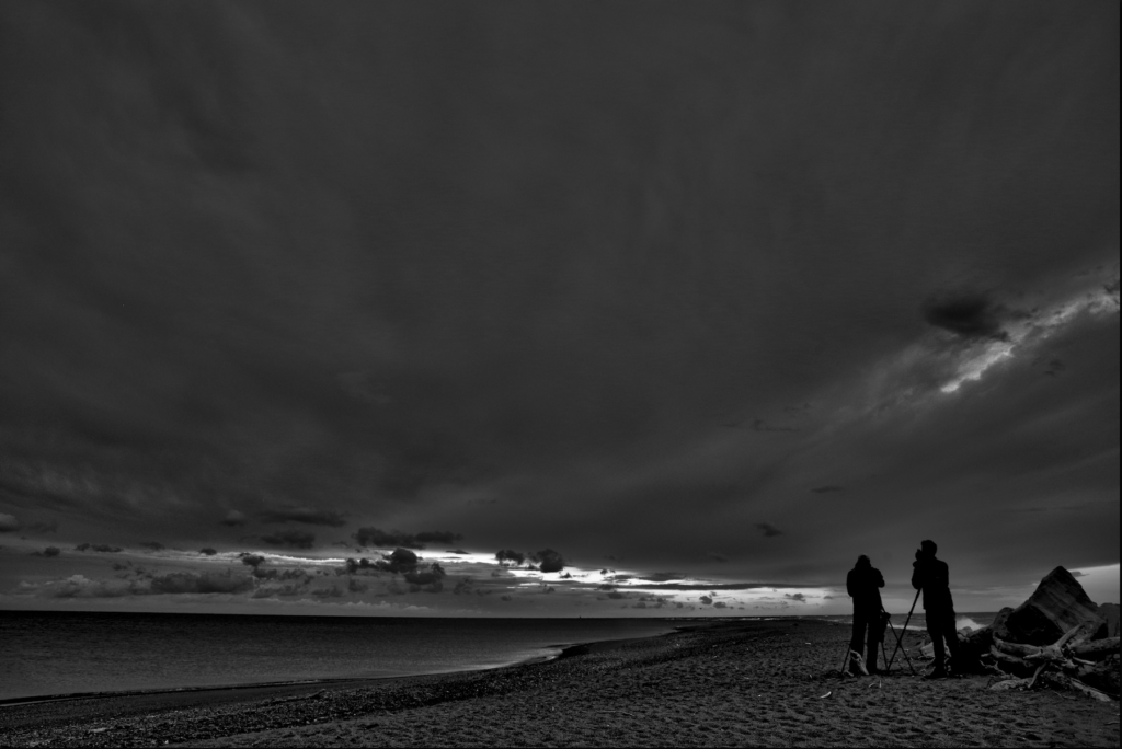 2 bird watcher in the early morning with a dramatic sky in the background