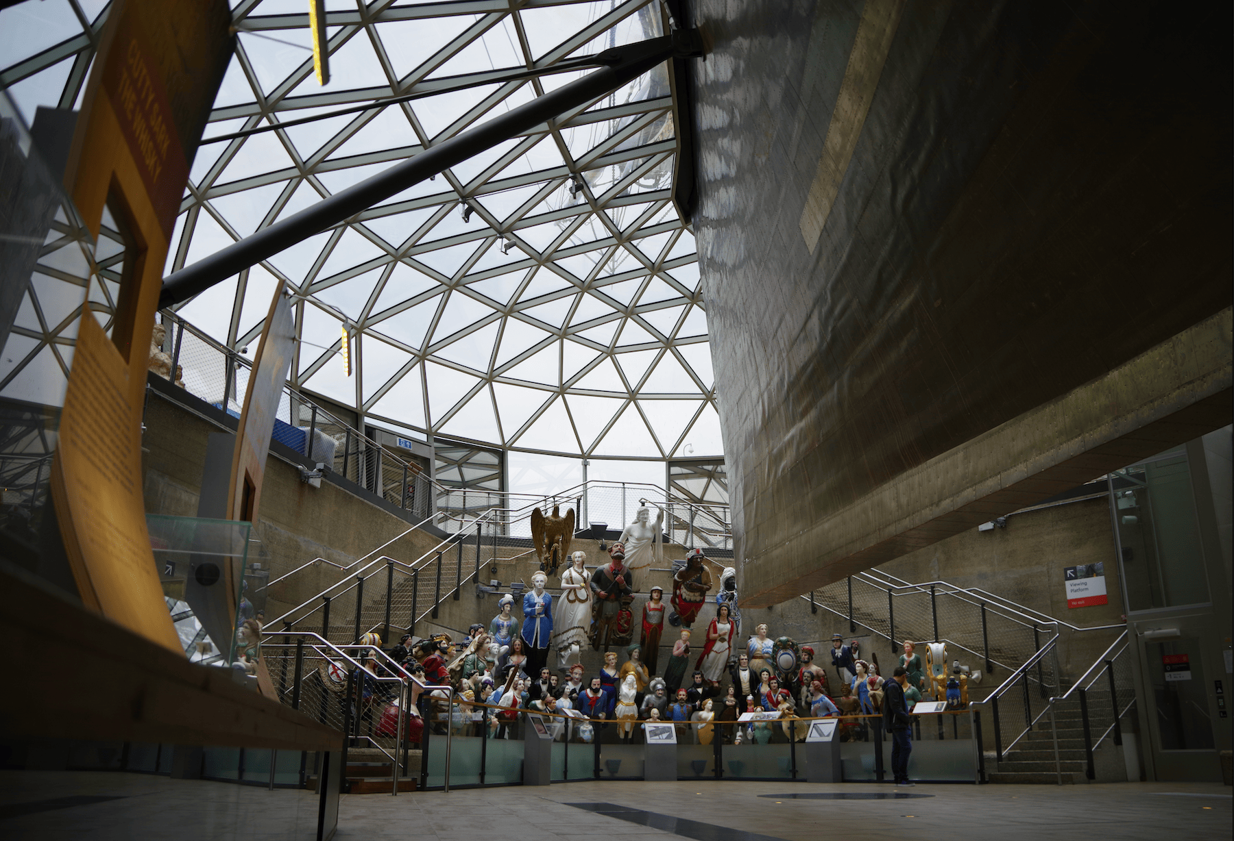 a collection of ship figureheads arranged underneath the hull of the Cut Sark